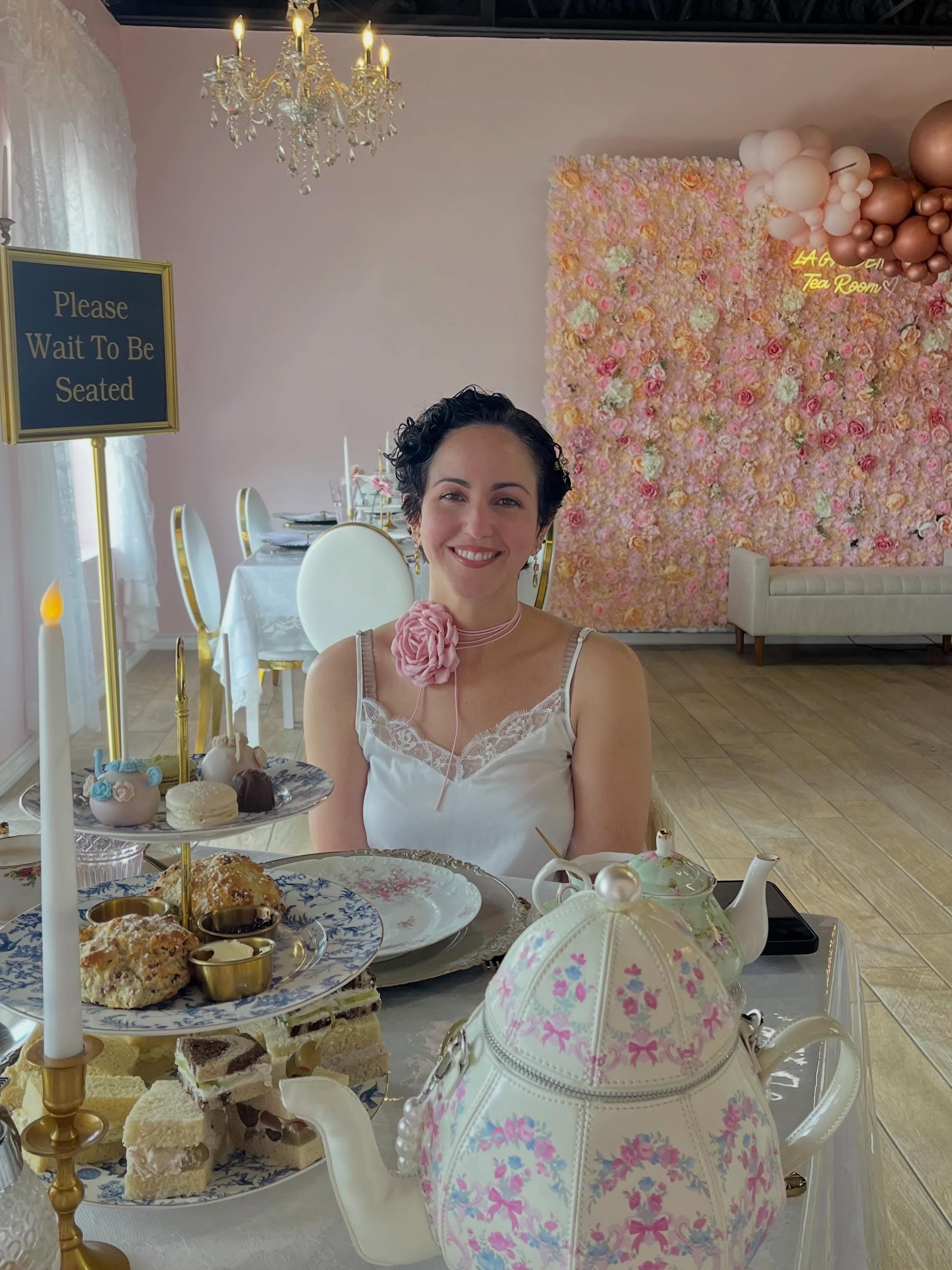 A guest seated at a set tea table inside the floral tea room.